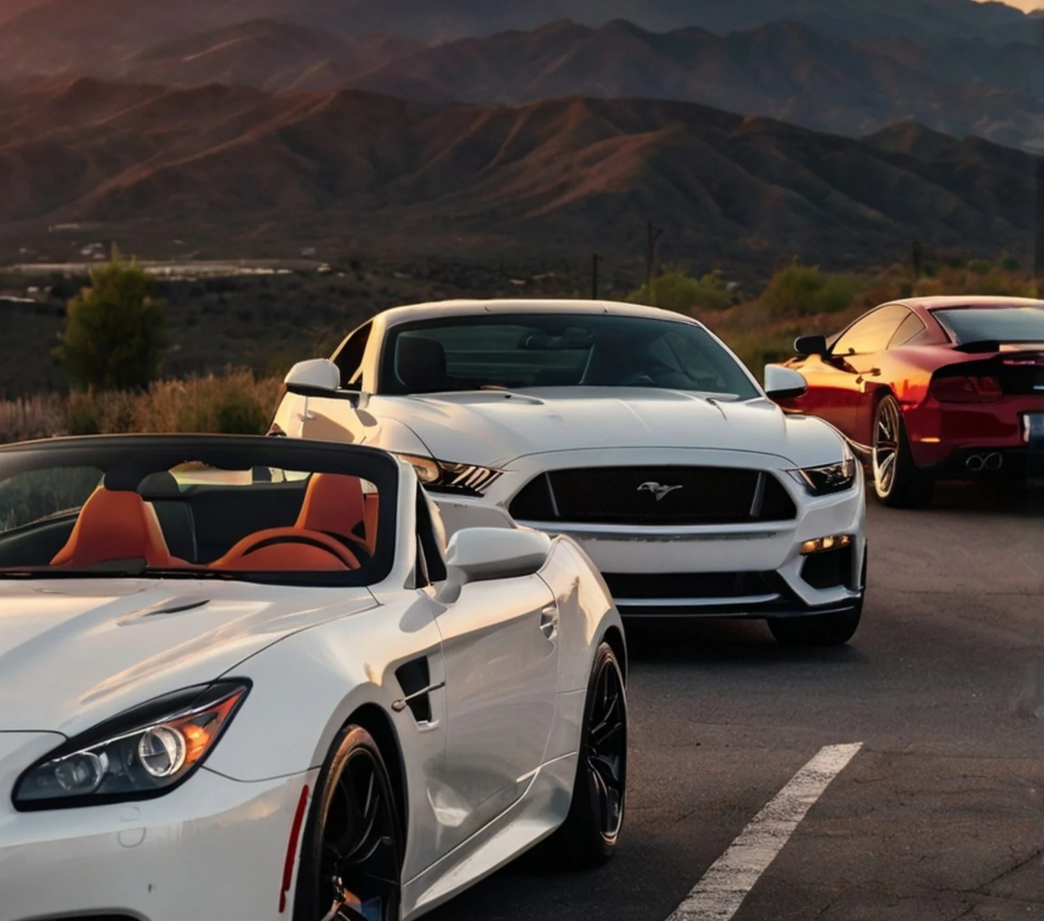 Sports cars parked on an open road below mountains at sunset