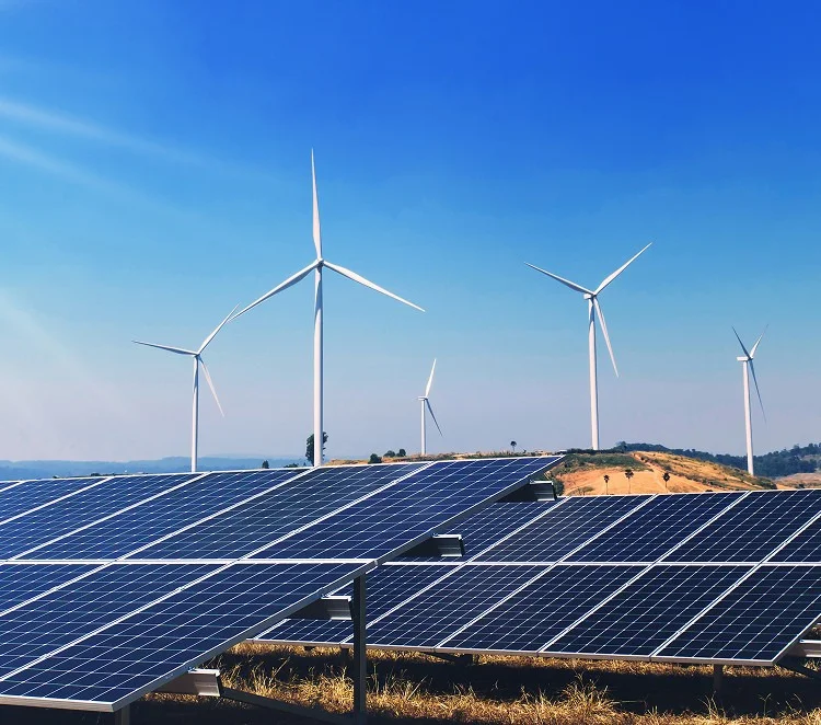 Solar panels in front of wind turbines under a clear blue sky